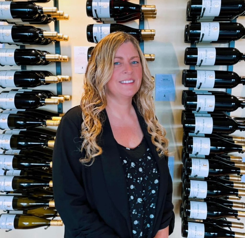 CFO Jeanine smiling in front of wine bottles