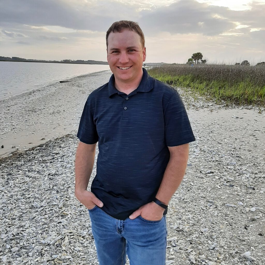 Vineyard manager Kirby standing on a beach smiling