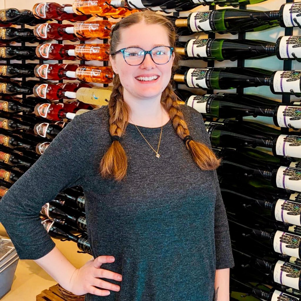 Canandaigua Tasting room manager smiling in front bottles